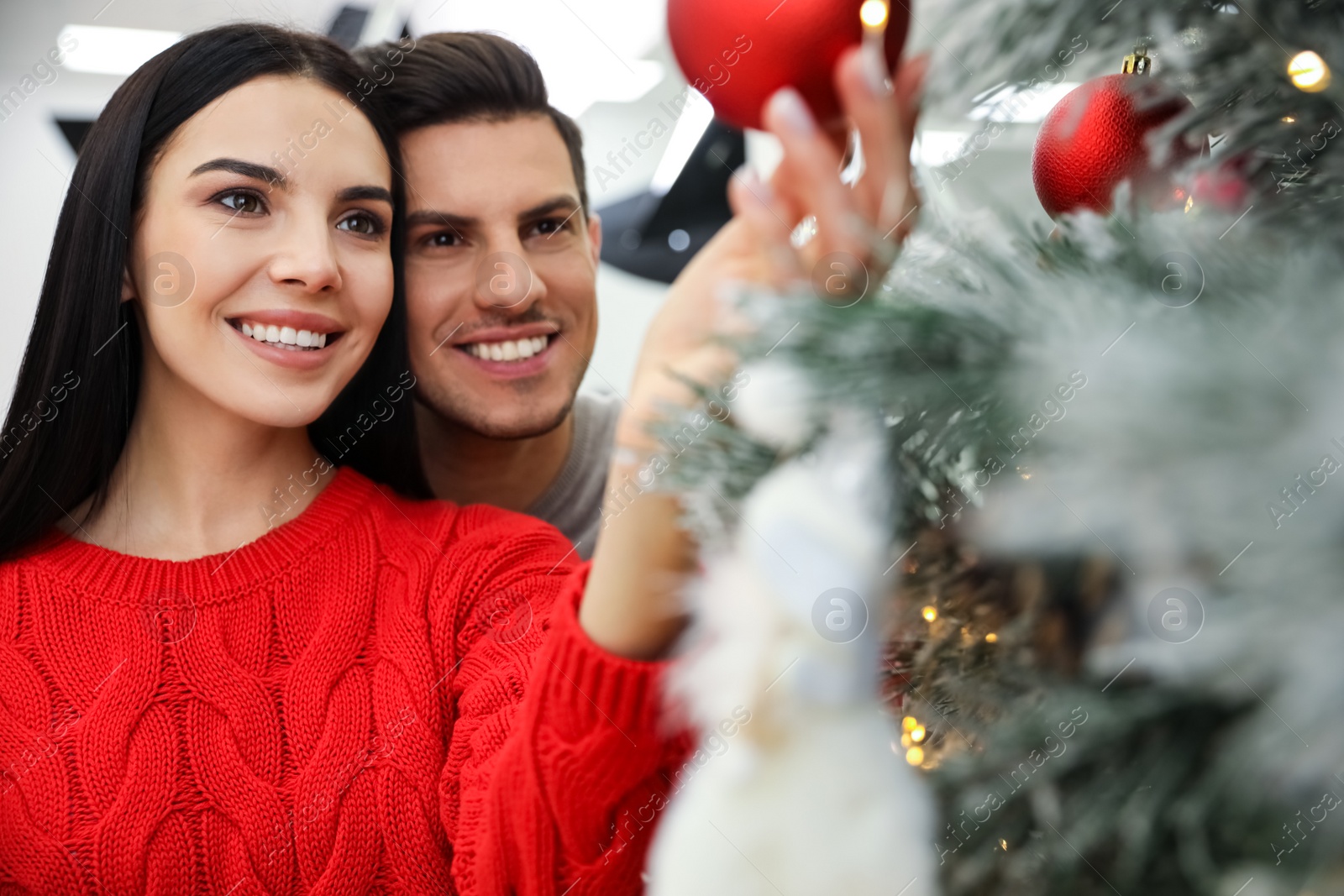 Photo of Happy couple decorating Christmas tree at home