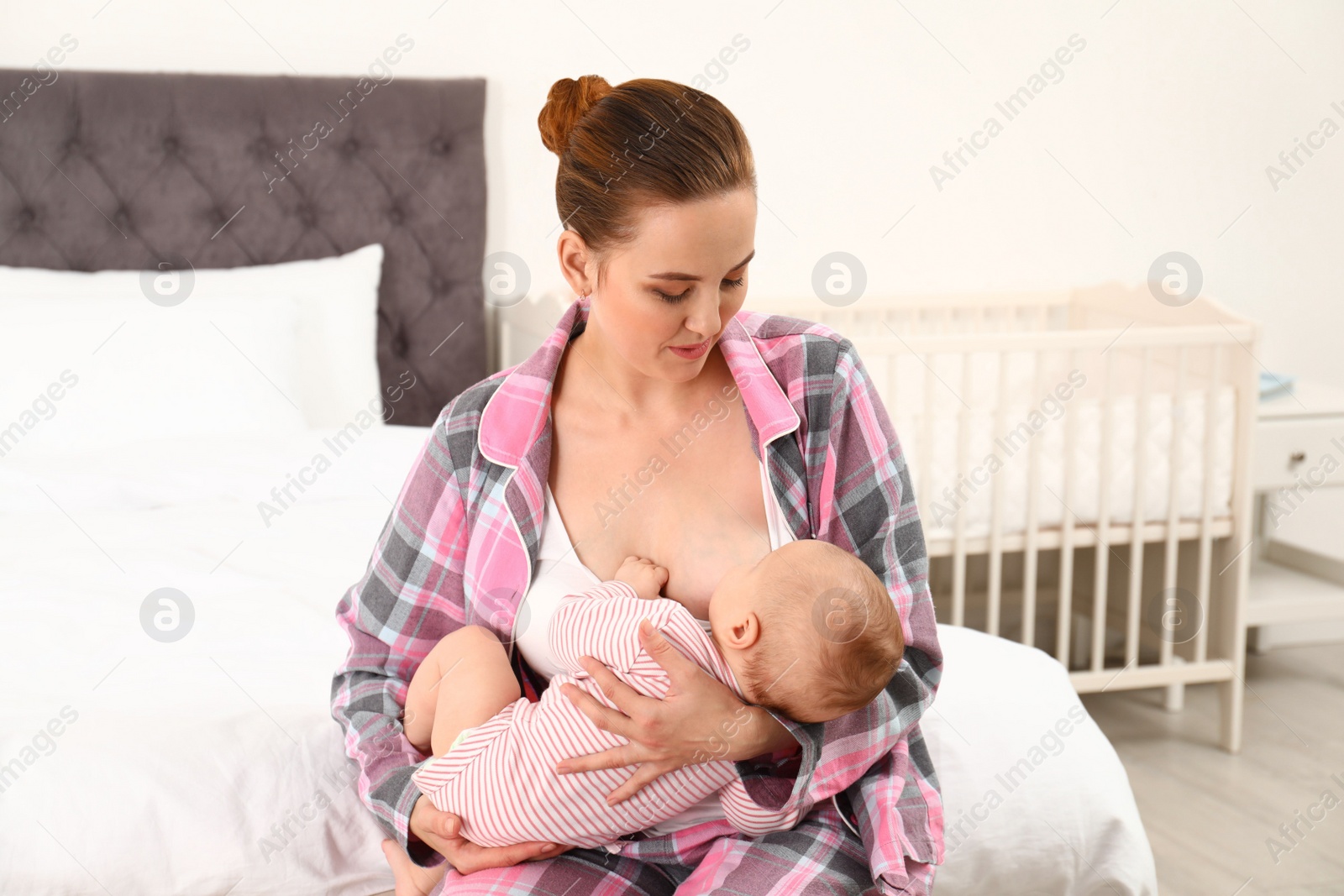 Photo of Young woman breastfeeding her little baby in bedroom