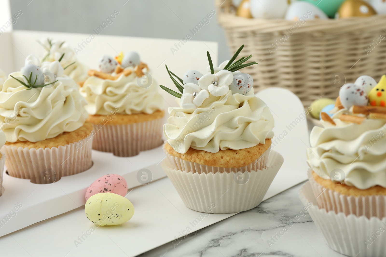 Photo of Tasty Easter cupcakes with vanilla cream on white marble table