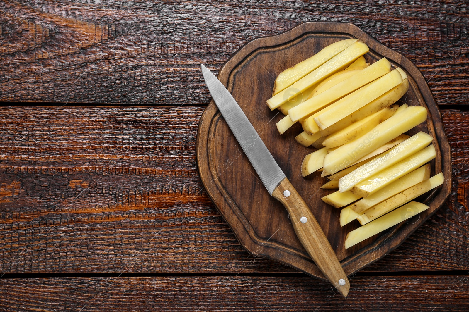 Photo of Cut raw potatoes and knife on wooden table, top view. Space for text