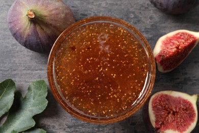 Photo of Bowl with tasty sweet jam and fresh figs on grey table, flat lay