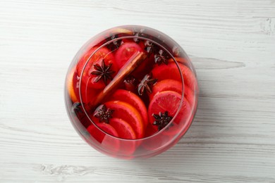 Photo of Glass bowl of delicious aromatic punch drink on white wooden table, top view