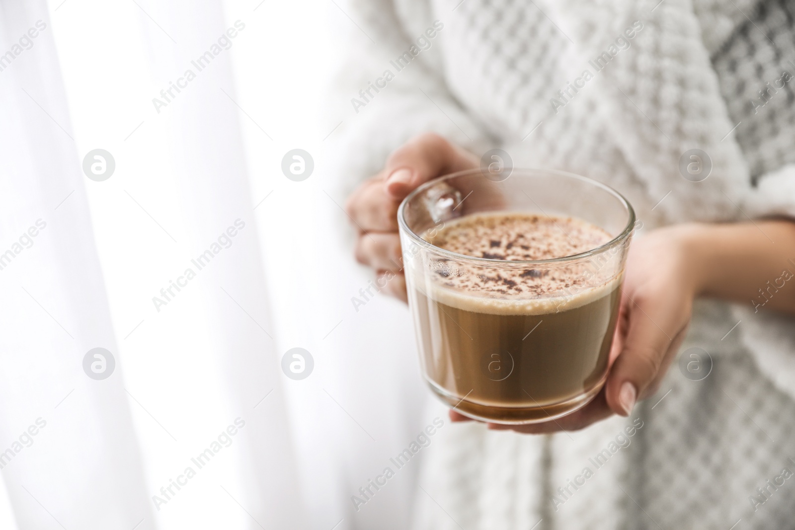 Photo of Woman with cup of hot drink near window at home in morning, closeup. Space for text