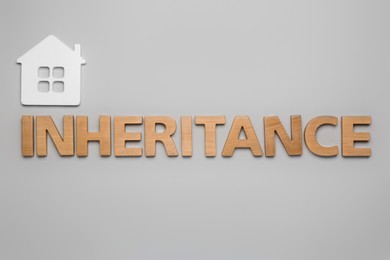 Photo of Word Inheritance made with wooden letters and house model on light background, flat lay