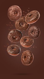 Image of Many sweet tasty donuts with chocolate crumbs falling on brown background