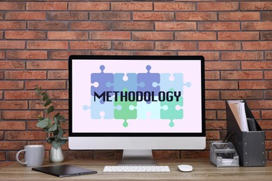 Image of Methodology concept. Workplace with modern computer on wooden table near brick wall