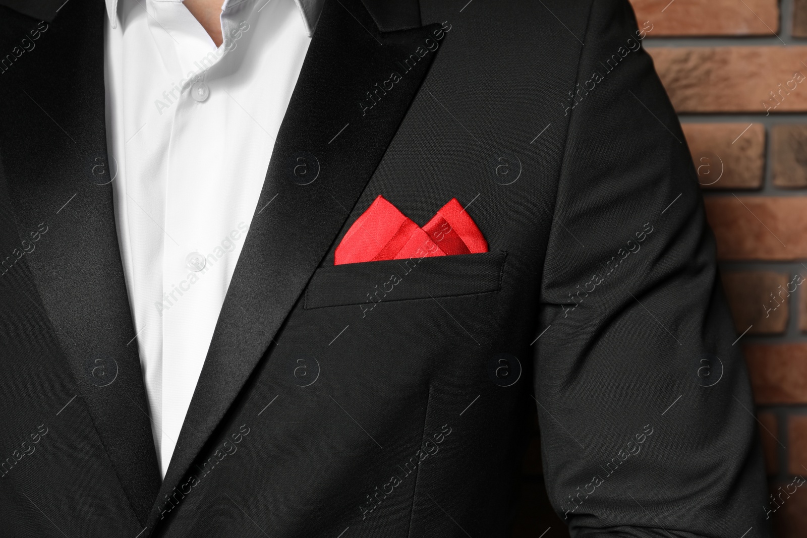 Photo of Man with handkerchief in breast pocket of his suit near brick wall, closeup