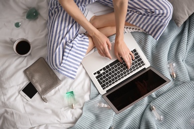 Female blogger with laptop on bed, top view
