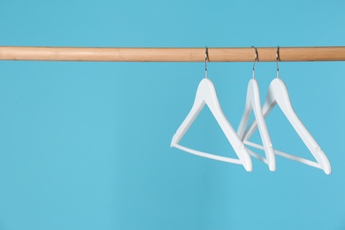 Photo of Wooden rack with clothes hangers on color background, space for text