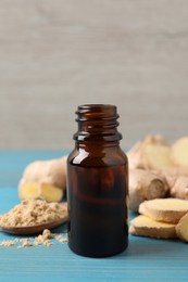 Glass bottle of essential oil and ginger root on light blue wooden table