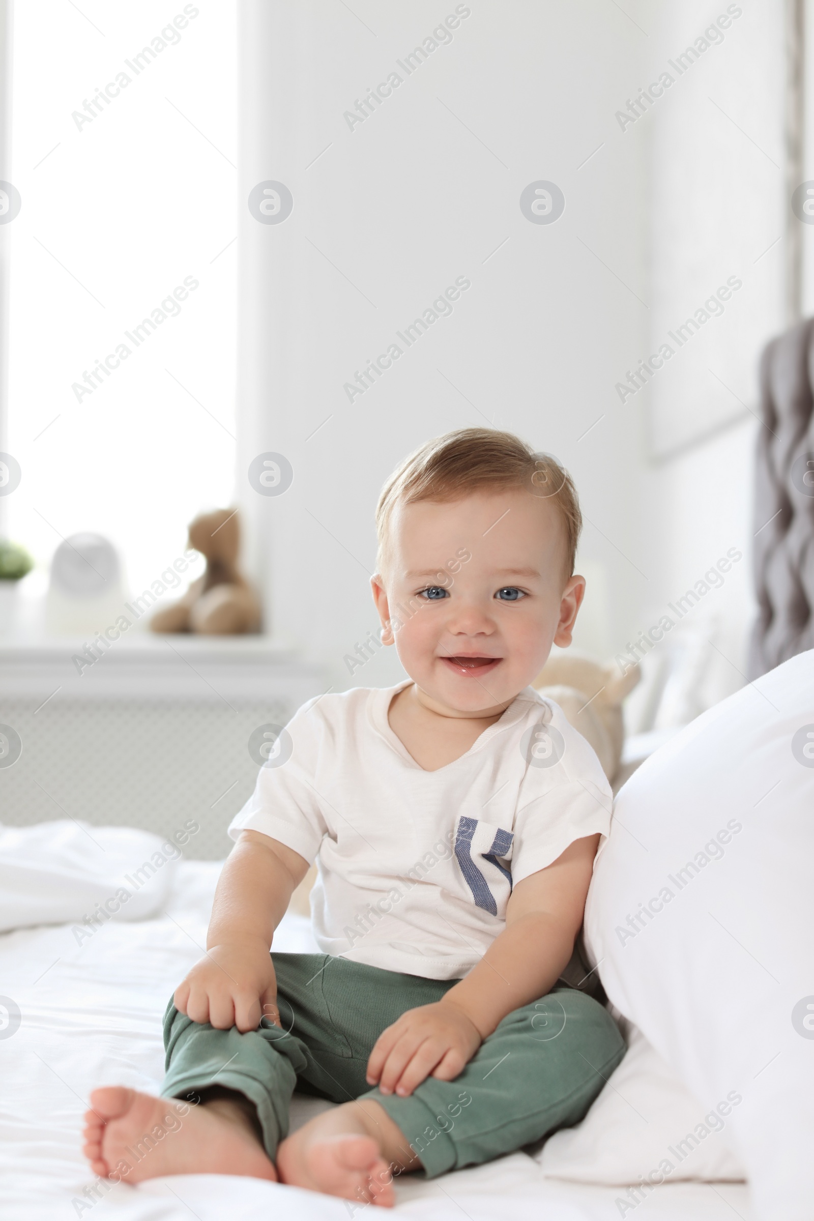Photo of Adorable little baby sitting on bed at home