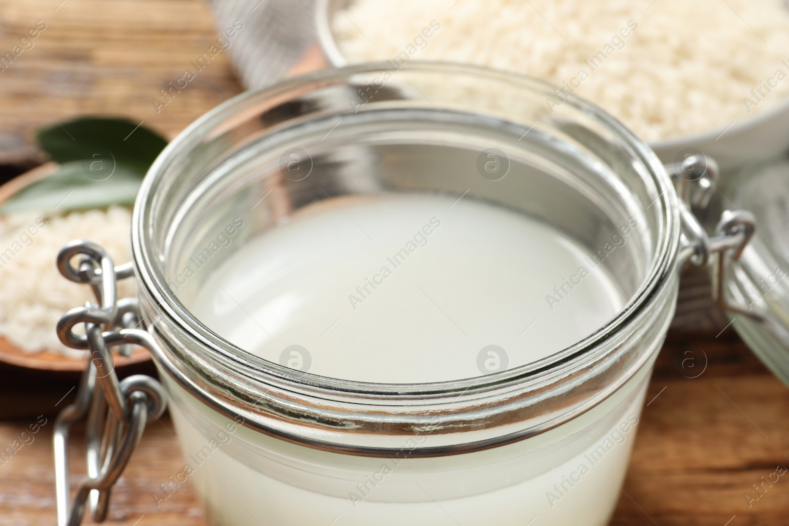 Photo of Glass jar with rice water on wooden table, closeup