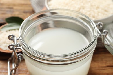 Photo of Glass jar with rice water on wooden table, closeup