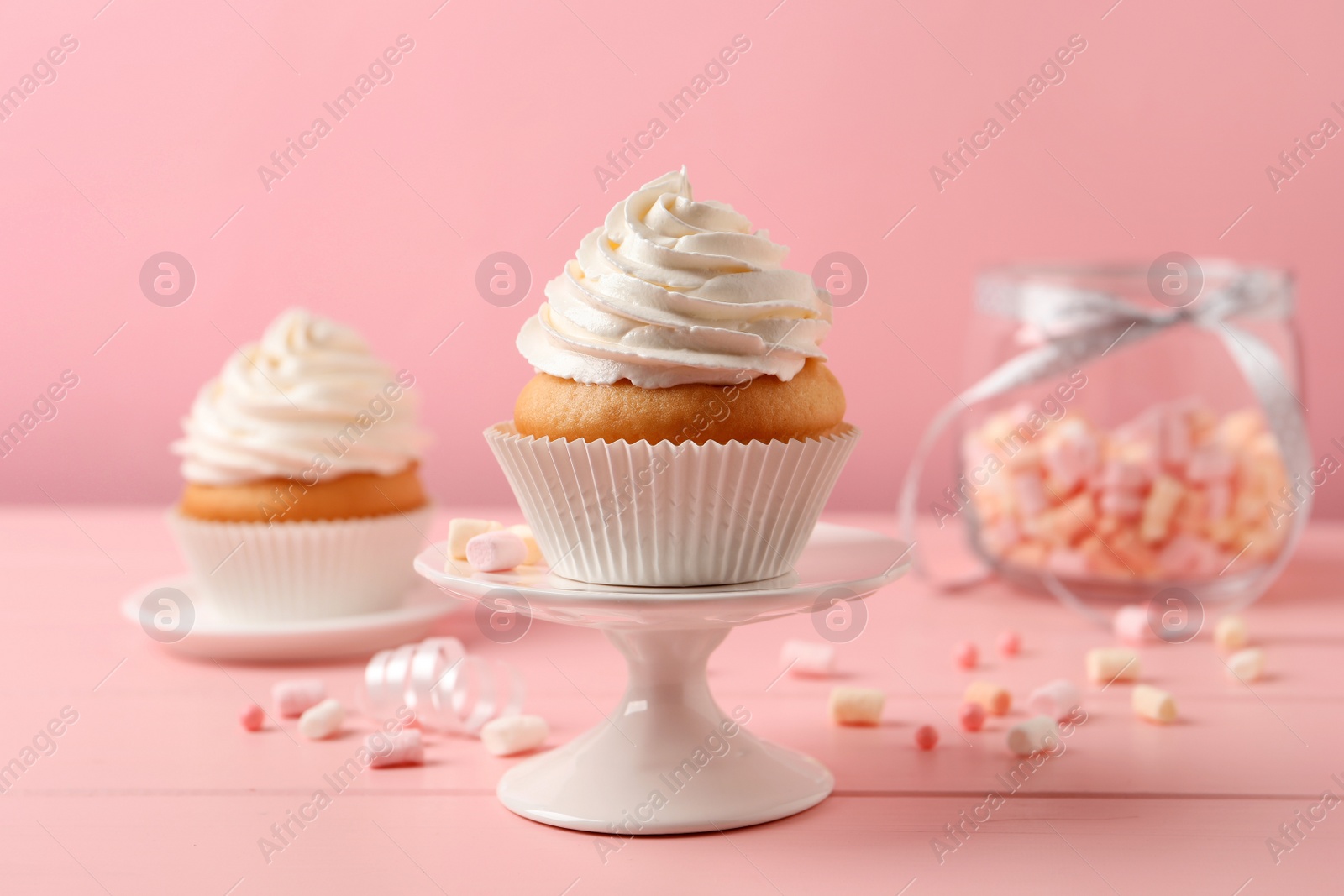 Photo of Delicious cupcakes decorated with cream on pink wooden table