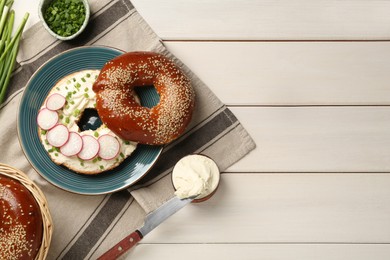Photo of Delicious bagel with cream cheese, green onion and radish on white wooden table, flat lay. Space for text