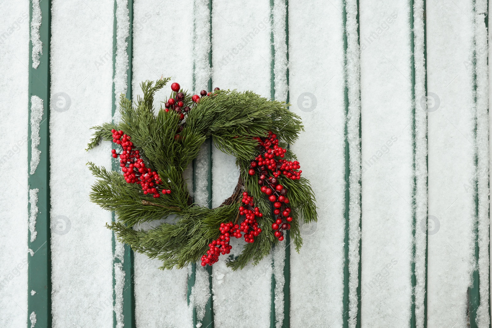 Photo of Beautiful Christmas wreath on metal surface covered with snow, top view. Space for text