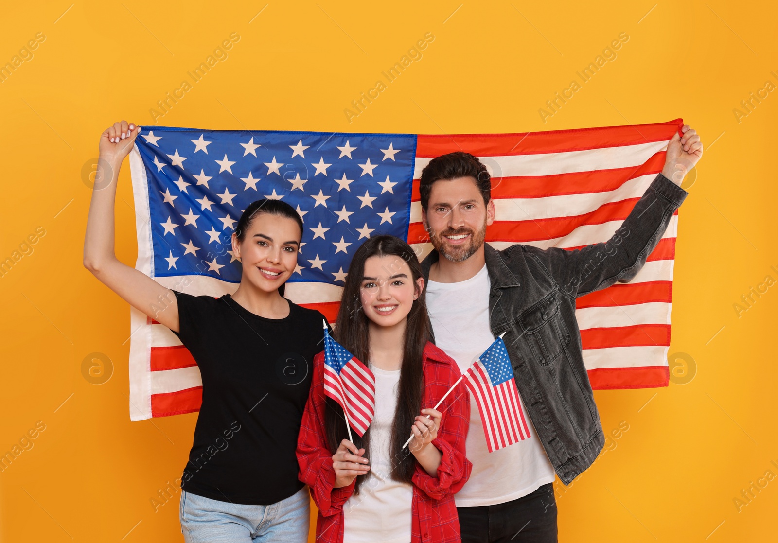 Photo of 4th of July - Independence Day of USA. Happy family with American flags on yellow background