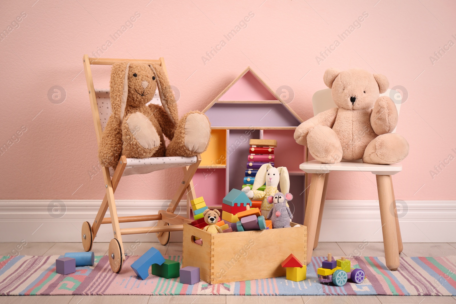 Photo of Set of different cute toys on floor near pink wall