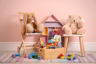 Set of different cute toys on floor near pink wall