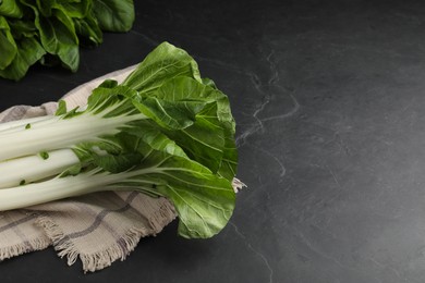 Photo of Fresh green pak choy cabbages on black table, space for text
