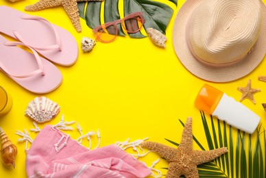 Frame of different beach objects on yellow background, flat lay. Space for text