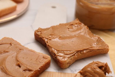Photo of Toasts with tasty nut butter on white table, closeup