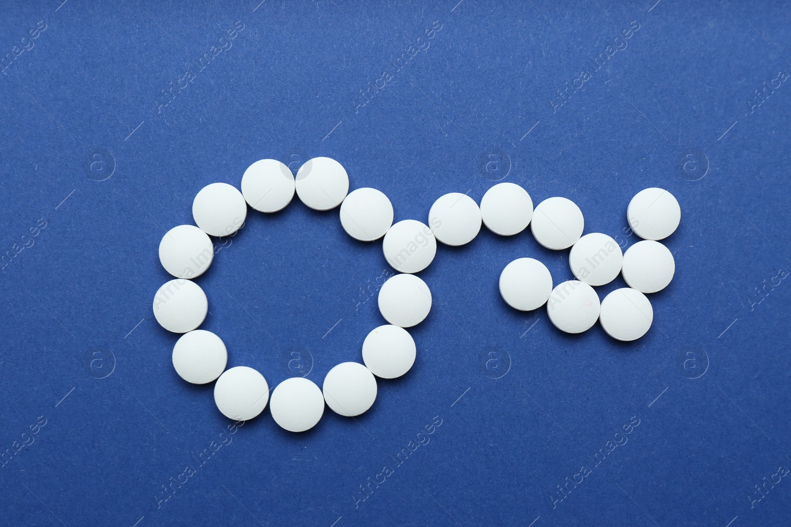 Photo of Male sign with bent arrow of white pills symbolizing potency problems on blue background, flat lay