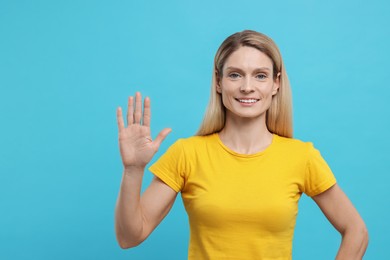Woman giving high five on light blue background. Space for text