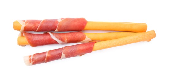 Delicious grissini sticks with prosciutto on white background, top view