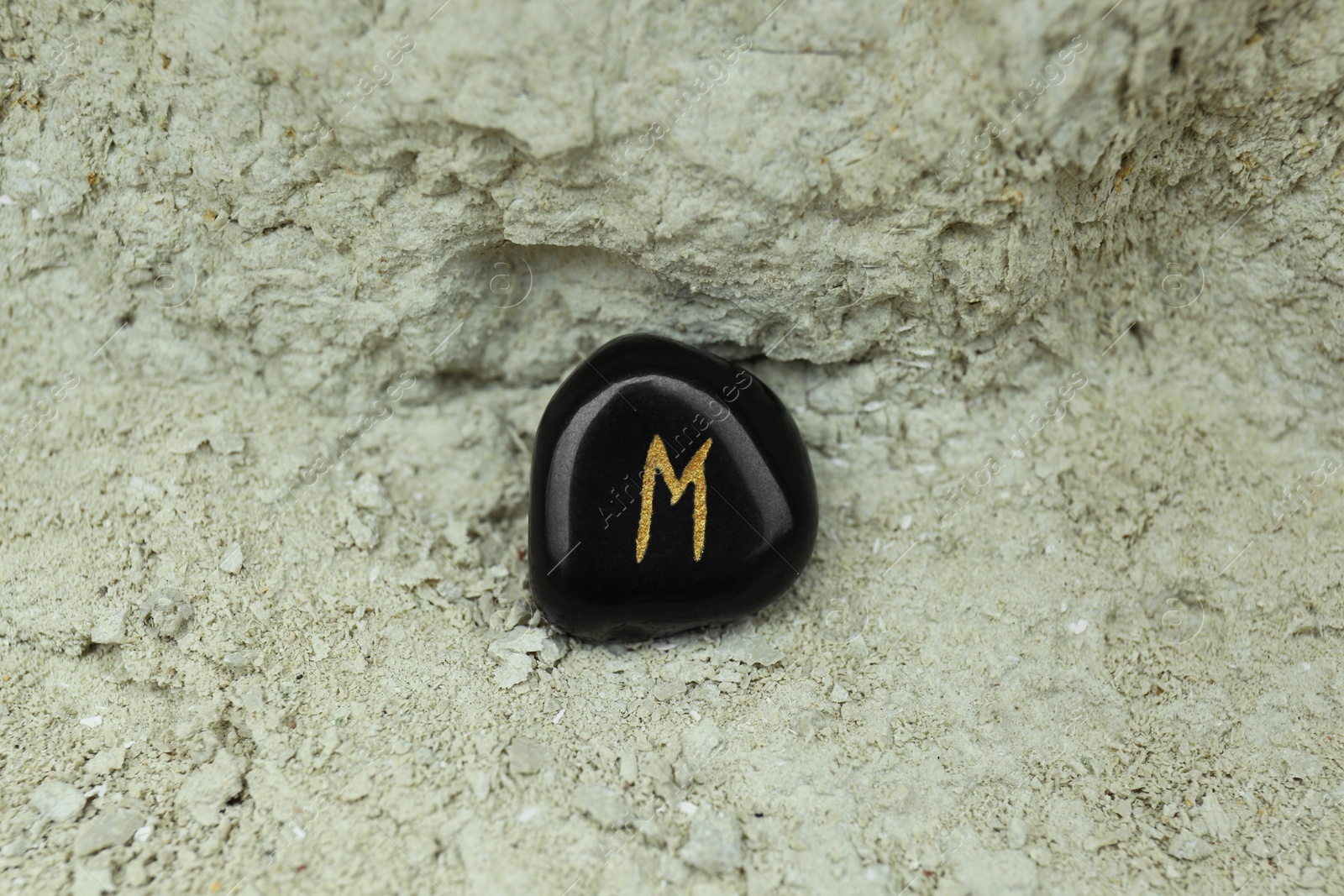 Photo of Black rune Ehwaz on stone outdoors, closeup