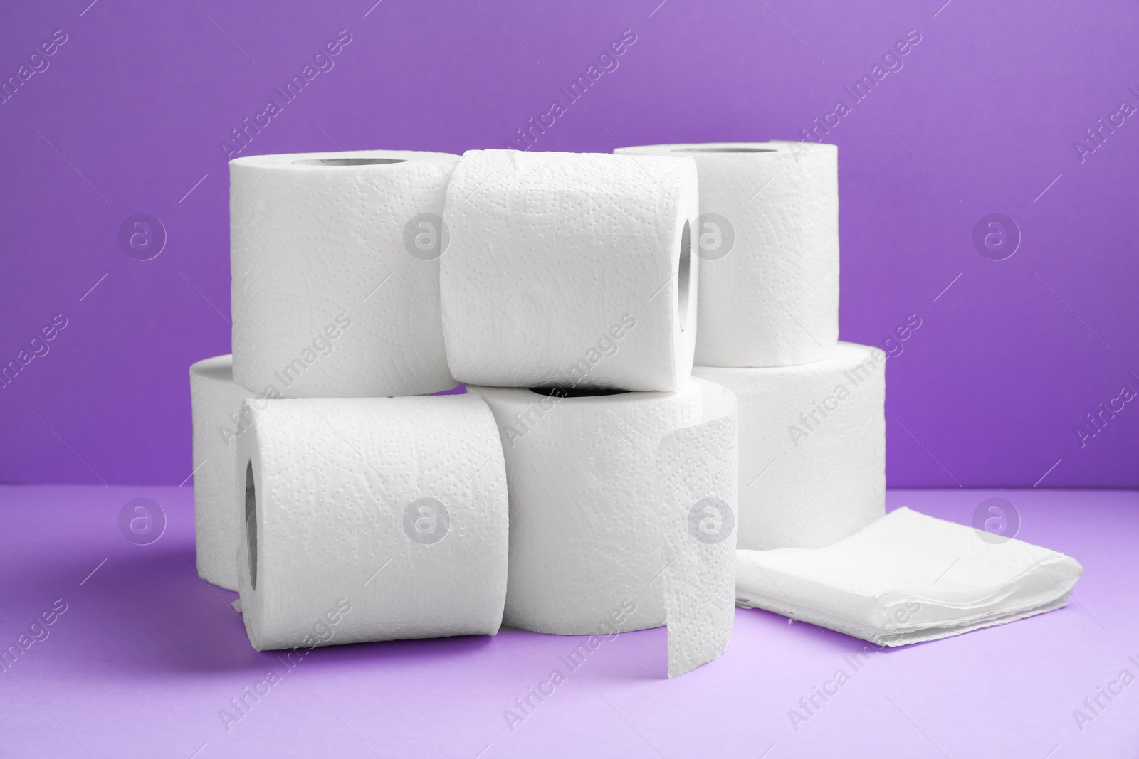 Photo of Soft toilet paper rolls on violet background