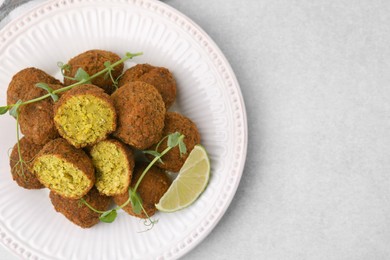 Photo of Delicious falafel balls, lime slice and microgreens on light table, top view. Space for text