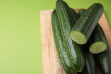 Photo of Fresh cucumbers on green background, closeup. Space for text