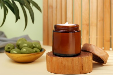 Jar of cream with olive essential oil on wooden table. Space for text