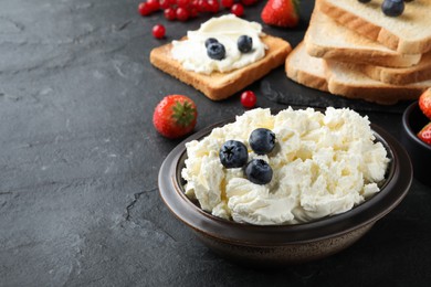 Tasty cream cheese, fresh berries and bread slices on black table, space for text