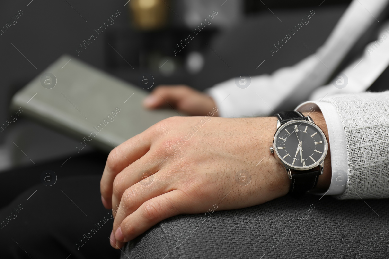 Photo of Businessman with luxury wrist watch on blurred background, closeup