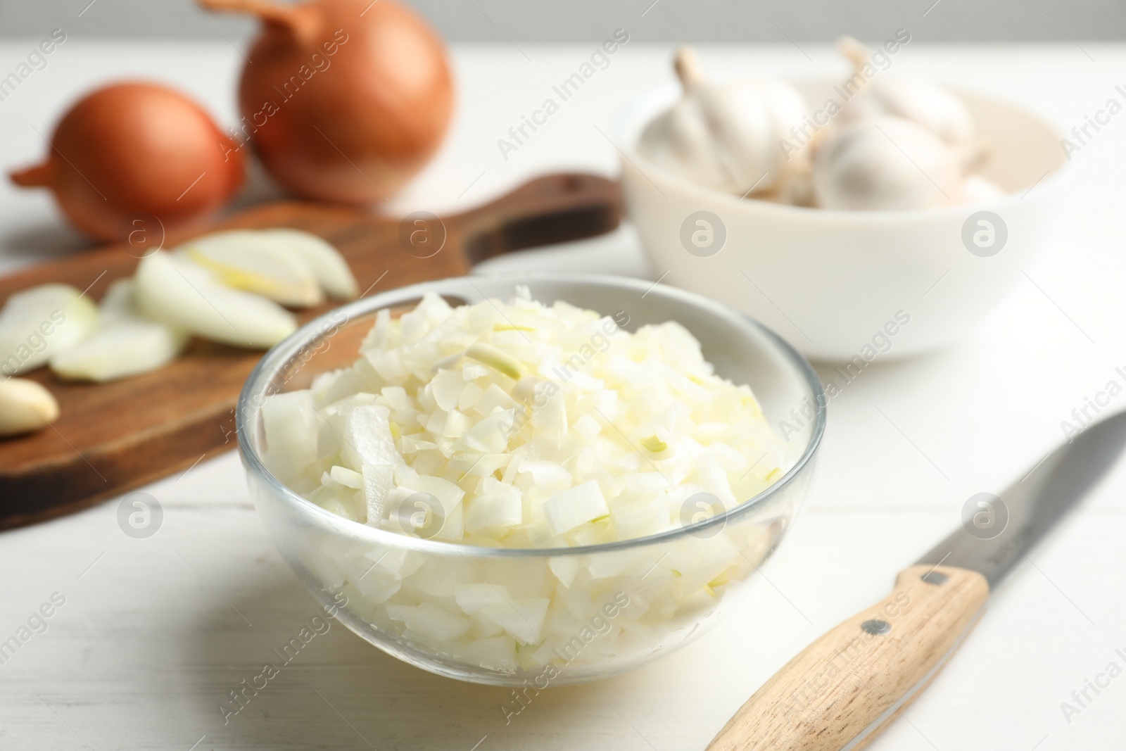 Photo of Chopped onion in bowl on white wooden table