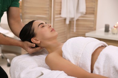 Woman receiving professional neck massage on couch in spa salon