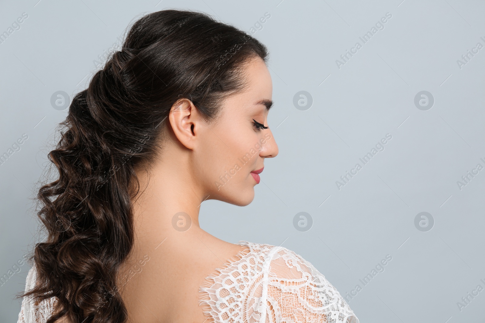 Photo of Young bride with beautiful wedding hairstyle on light grey background. Space for text