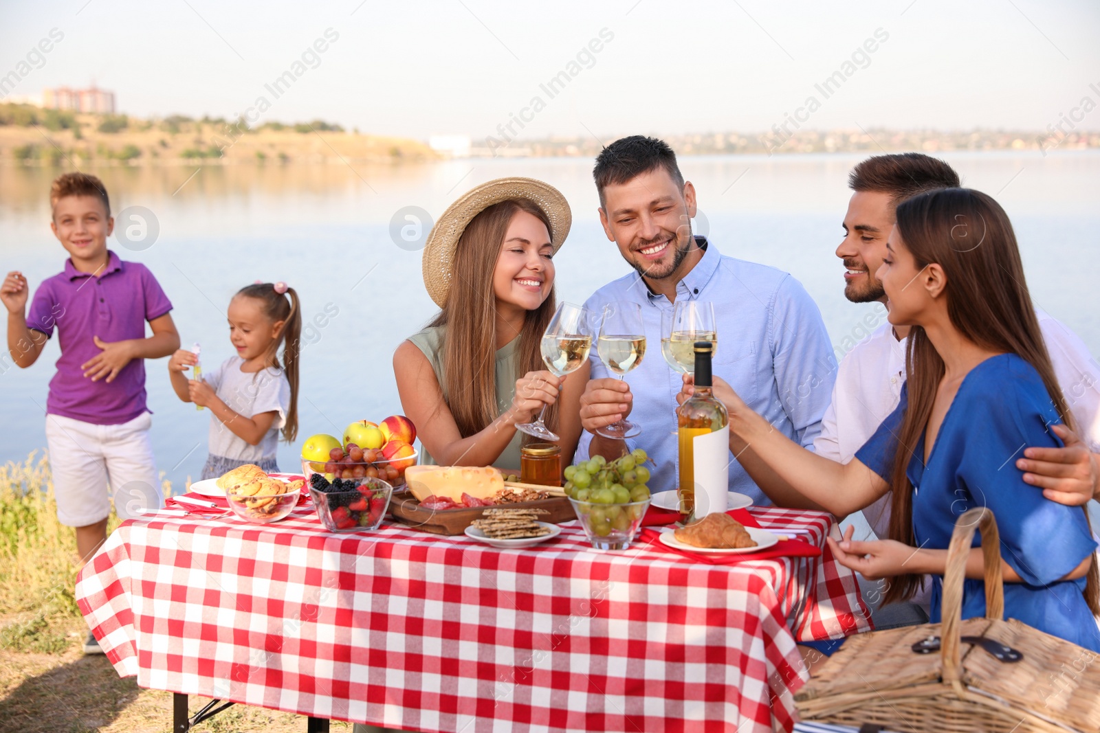 Photo of Happy families with little children having picnic at riverside