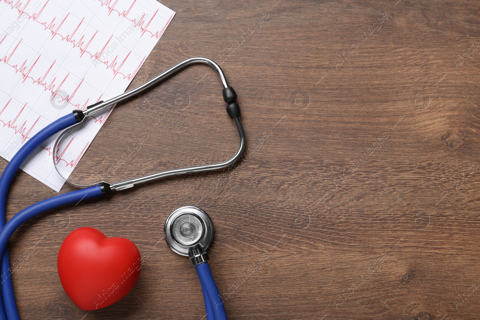 Photo of Stethoscope, cardiogram, red decorative heart and space for text on wooden background, flat lay. Cardiology concept