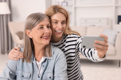 Happy mature mother and her daughter taking selfie at home