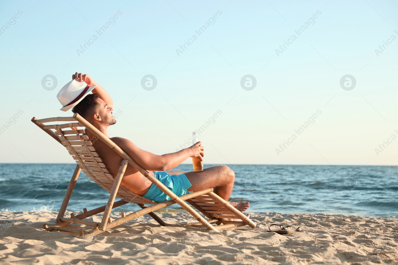 Photo of Young man relaxing in deck chair on beach near sea