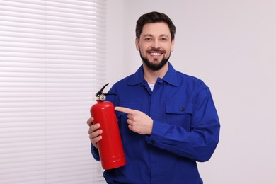 Photo of Man in uniform with fire extinguisher indoors