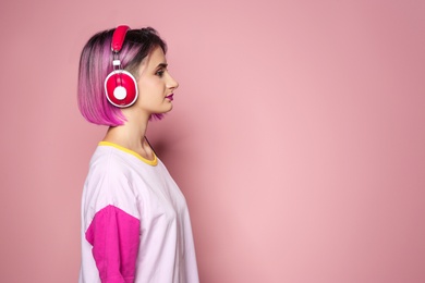 Photo of Young woman with trendy hairstyle listening to music against color background