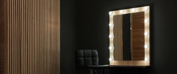 Image of Makeup room. Stylish mirror with light bulbs and chair indoors, banner design