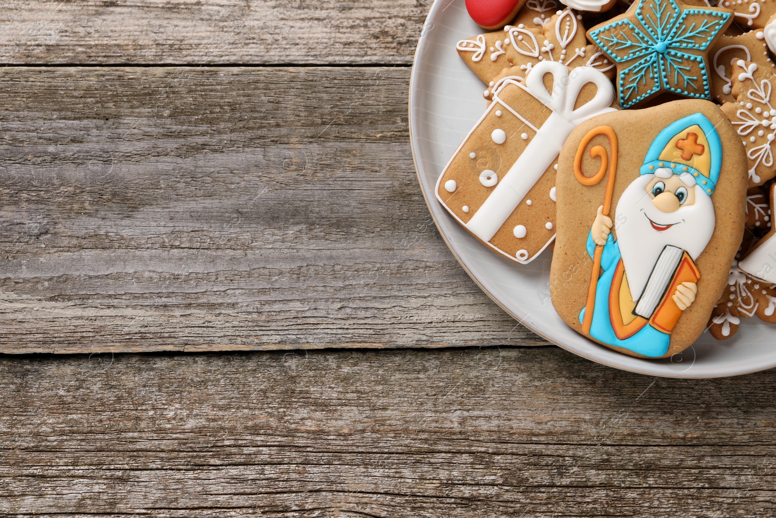 Photo of Tasty gingerbread cookies on wooden table, top view with space for text. St. Nicholas Day celebration