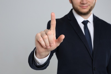 Photo of Businessman touching something against grey background, focus on hand