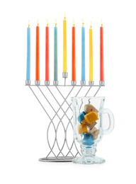 Hanukkah celebration. Menorah with colorful candles and dreidels in glass cup isolated on white