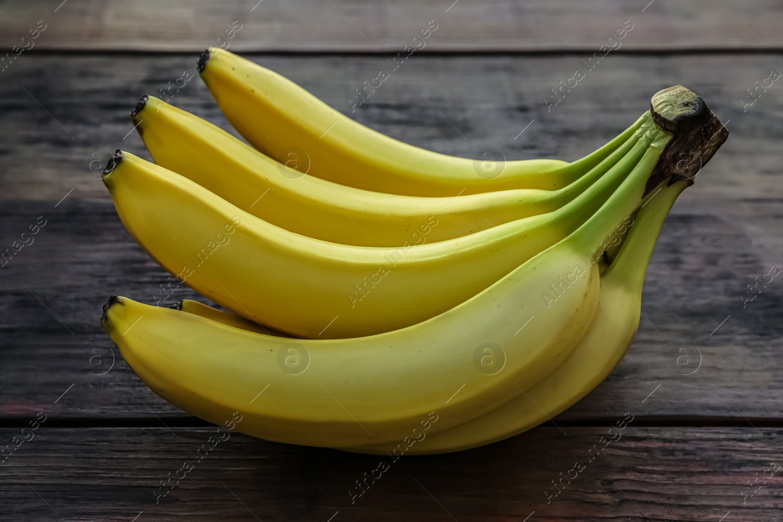 Photo of Bunch of ripe yellow bananas on wooden table